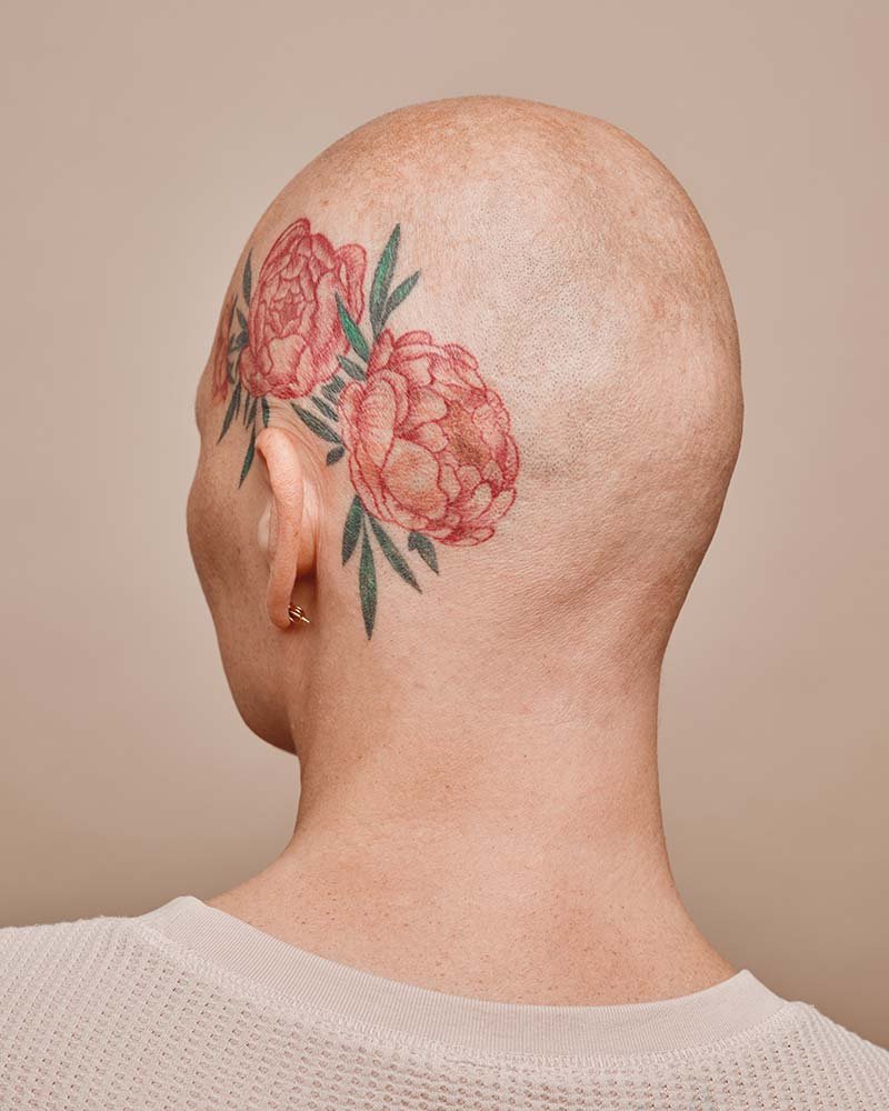 Vista trasera de una mujer calva con un tatuaje en la cabeza, mostrando un diseño artístico único y su estilo personal.