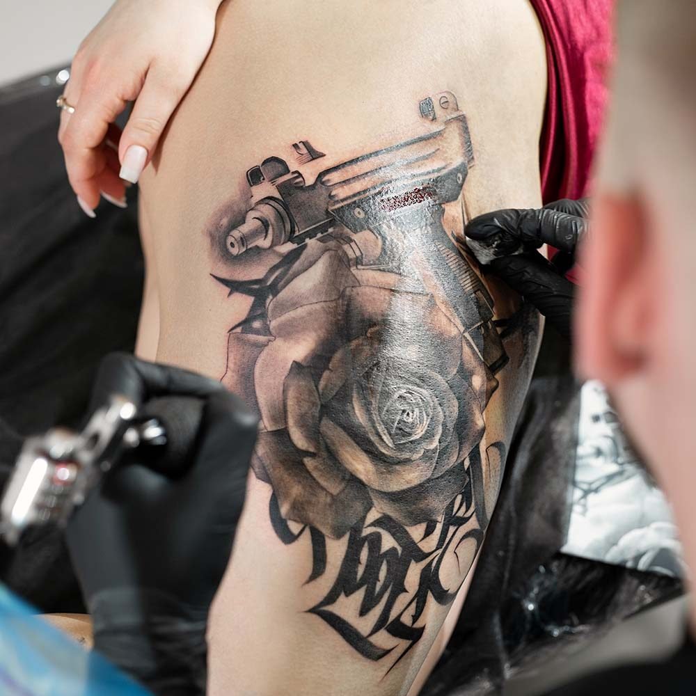 Primer plano de un tatuador barbudo trabajando en un diseño, mostrando pasión y destreza artística en el proceso de tatuar.