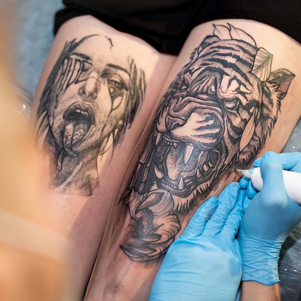 Artista de tatuajes profesional trabajando en el diseño de un tatuaje en el brazo de una mujer, destacando precisión y creatividad en el arte corporal.